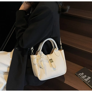 Detail of cream bucket bag with lychee texture leather and pearl lace bow accessory