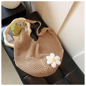 Detail of hand-woven beige hobo bag with hollow mesh structure and white daisy floral accent
