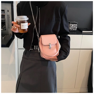 Detailed view of a pink small flap crossbody bag with a silver oval twist lock and chain