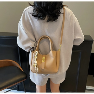 Dettaglio borsa a secchiello in pelle color cammello con chiusura oro e foulard