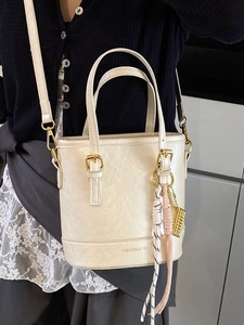 Minimalist cream white bucket bag in PU leather with woven charm and gold hardware detail