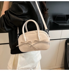 Détail du sac Boston crème avec nœuds élégants et une bandoulière amovible