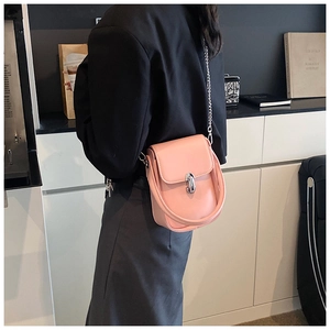 Detail view of pink crossbody bag with silver twist lock and chain strap on model