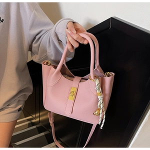 Dettaglio borsa a secchiello rosa in pelle martellata con chiusura e orsetto oro