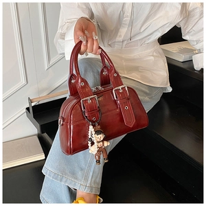 Detail of dark red vintage Boston bag featuring silver buckles and cute pearl charm
