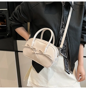 Détail du sac Boston crème avec nœuds élégants et texture en cuir brillant chic
