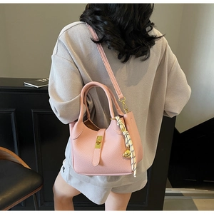 Borsa a tracolla rosa con trama litchi, chiusura girevole oro e ciondolo intrecciato