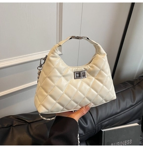 Dettaglio borsa a tracolla beige trapuntata con chiusura a rotazione e catena argento