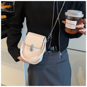 Detail of cream crossbody bag with silver oval twist lock on a black blazer outfit