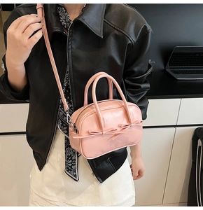Vue détaillée du sac Boston rose brillant avec nœuds élégants et détails argentés