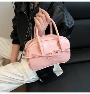 Détail du sac Boston rose avec nœuds décoratifs et texture en cuir synthétique poli