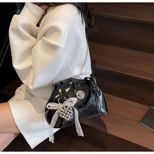 Détail du sac à main noir avec fermoir argenté et breloque élégante en dentelle