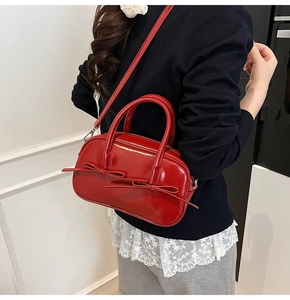 Détail macro du sac Boston rouge brillant avec nœuds et bandoulière réglable pratique
