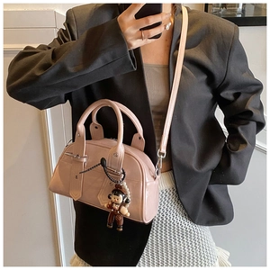 Detail of a pink patent leather Boston bag featuring a trendy doll charm and pearl chain