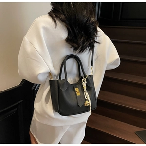 Dettaglio borsa a secchiello nera in pelle con chiusura dorata e foulard decorativo