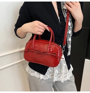 Détail du sac Boston en cuir verni rouge avec nœuds élégants et finitions métalliques argent