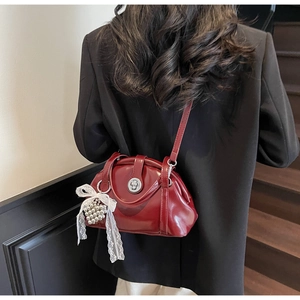 Détail du sac bordeaux avec nœud en dentelle blanche et perle porté par un mannequin