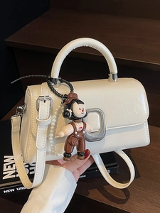 Elegant cream leather handbag with silver square buckle and cute cartoon boy charm