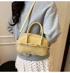 Détail du sac à main en cuir verni jaune clair avec deux nœuds et bandoulière en métal
