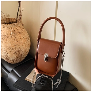 Detail view of a vintage brown leather handbag with silver cylindrical clasp and chain