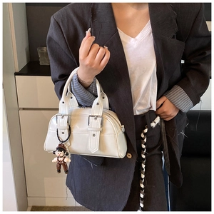 Detailed shot of white PU leather Boston bag with belt buckles and doll charm