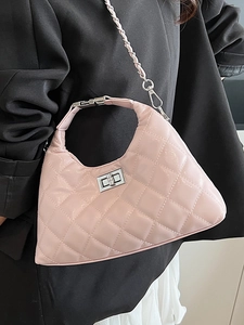 Borsa a tracolla trapuntata rosa con chiusura argentata su sfondo di un blazer nero elegante