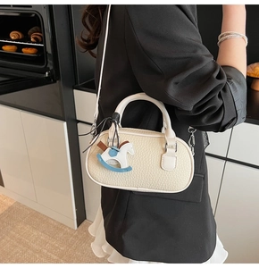 Dettaglio della mini borsa Boston color crema con texture litchi e ciondolo a cavallo