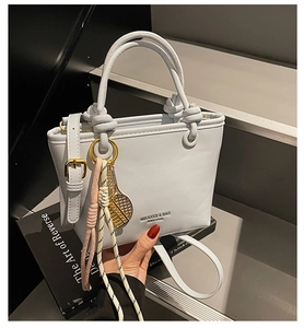 Detail of light blue crossbody bucket bag with knot handle and tennis racket charm