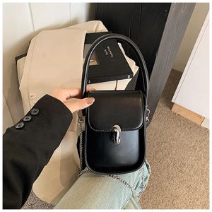 Close-up of black leather mini handbag with silver chain strap and metal twist lock