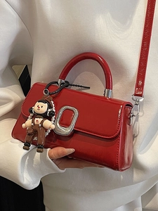 Elegant red patent leather crossbody bag with silver buckle and cute doll charm accessory