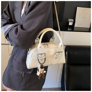 Fashionable cream bowler bag with silver buckles and pearl charm shown on model
