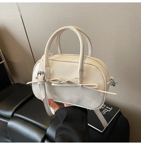 Détail du sac Boston blanc crème avec double nœud et bandoulière réglable pratique