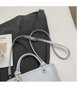 Detailed close-up of light grey-blue matte leather bucket bag with golden hardware