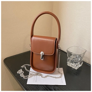 Close-up of brown vintage leather crossbody bag with silver chain and metal clasp
