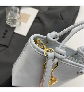 Close-up of light blue bucket bag with knot handle detail and gold hardware clasp