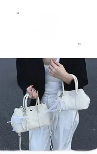 Détail du sac seau blanc cassé avec cuir grainé, noeud en dentelle et breloque en perle