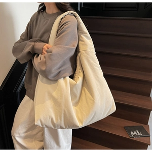 Vista dettagliata di una borsa tote imbottita crema indossata su una scala in legno scuro