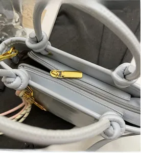 Detail of light blue bucket bag showing smooth gold zipper and knotted strap design