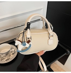 Dettaglio borsa in pelle a grana con ciondolo a cavallo e finiture metalliche argentate