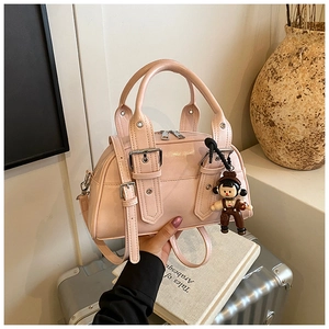 Detail showing pink glossy PU leather Boston bag with a cute bear charm and silver rivets