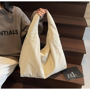 Dettaglio di una borsa tote trapuntata beige con texture imbottita e grande capacità