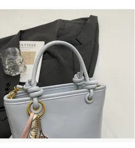 Close-up of light blue leather bucket bag with knotted handle and tennis racket charm