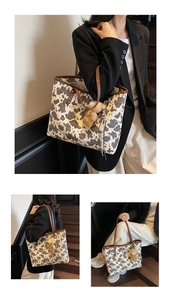 Detailed close-up of cow print tote bag featuring brown leather trim and a cute bear charm