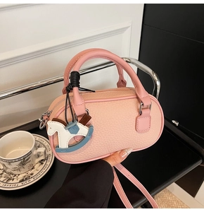 Dettaglio borsa Boston rosa in pelle martellata con ciondolo a forma di cavallino