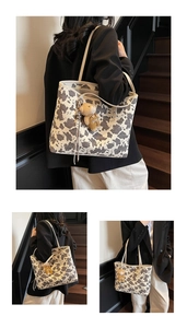 Detail view of cow print canvas tote bag with a cute plush bear charm in retro setting