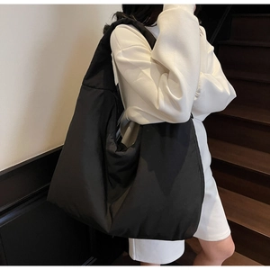 Dettaglio di una borsa tote nera stile nuvola con spalline larghe su una modella