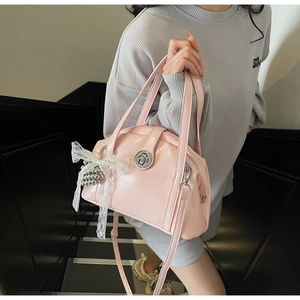 Sac coquille en cuir verni rose avec fermoir en métal et nœud en dentelle sur l'escalier