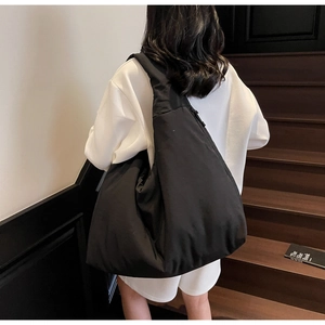 Dettaglio di una grande borsa a mezzaluna nera minimalista indossata da una modella