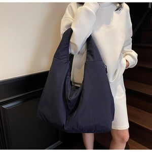 Dettaglio di una grande borsa tote in nylon blu navy con ampia tracolla e chiusura a zip