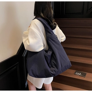 Grande borsa tote a mezzaluna blu navy minimalista portata a spalla da una modella